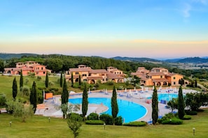A resort with multiple buildings, a central swimming pool, and a well-maintained lawn.