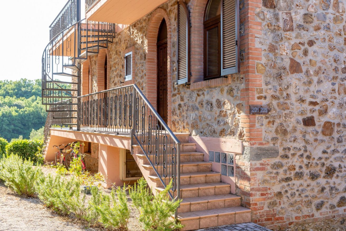 A stone building with a balcony, a staircase, and a door.