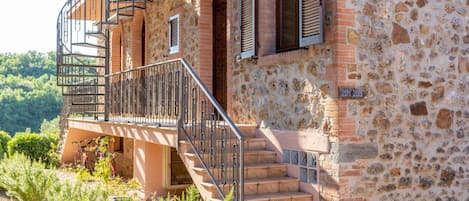 A stone building with a balcony, a staircase, and a door.