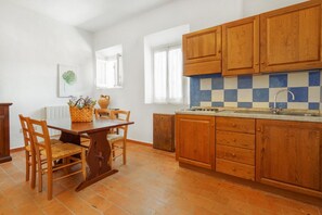A kitchen with wooden cabinets, a tiled backsplash, and a dining area with a table and chairs.