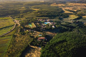 An aerial view of a rural area with a large estate featuring a swimming pool, multiple buildings, and extensive agricultural fields.