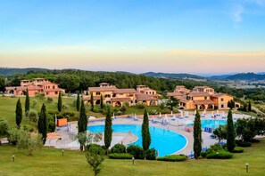 A resort with multiple buildings, a central swimming pool, and a well-maintained lawn.