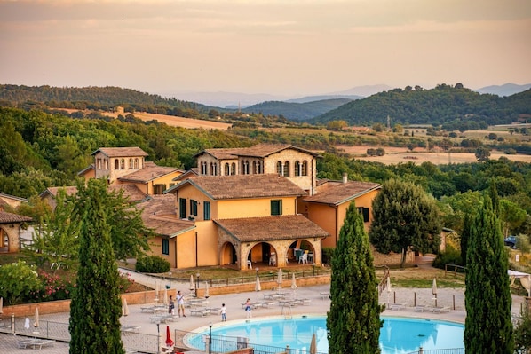 A villa with a swimming pool, surrounded by greenery and hills.