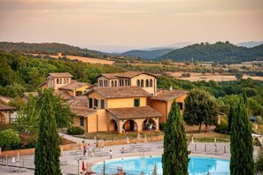 A villa with a swimming pool, surrounded by greenery and hills.