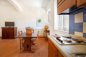 A kitchen with a dining table, chairs, a TV, a stove, and a window with a view.