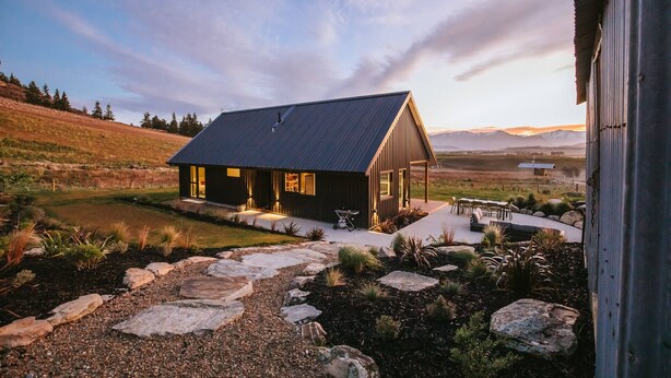 A modern house with a sloped roof, large windows, and a stone pathway leading to the entrance. - Ranger's Retreat - Secluded - Sleeps 4 (Lake Hawea)