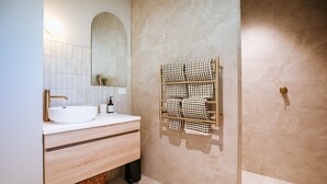 A modern bathroom with a white sink, gold faucet, and a towel rack with checkered towels. - Ranger's Retreat - Secluded - Sleeps 4 (Lake Hawea)