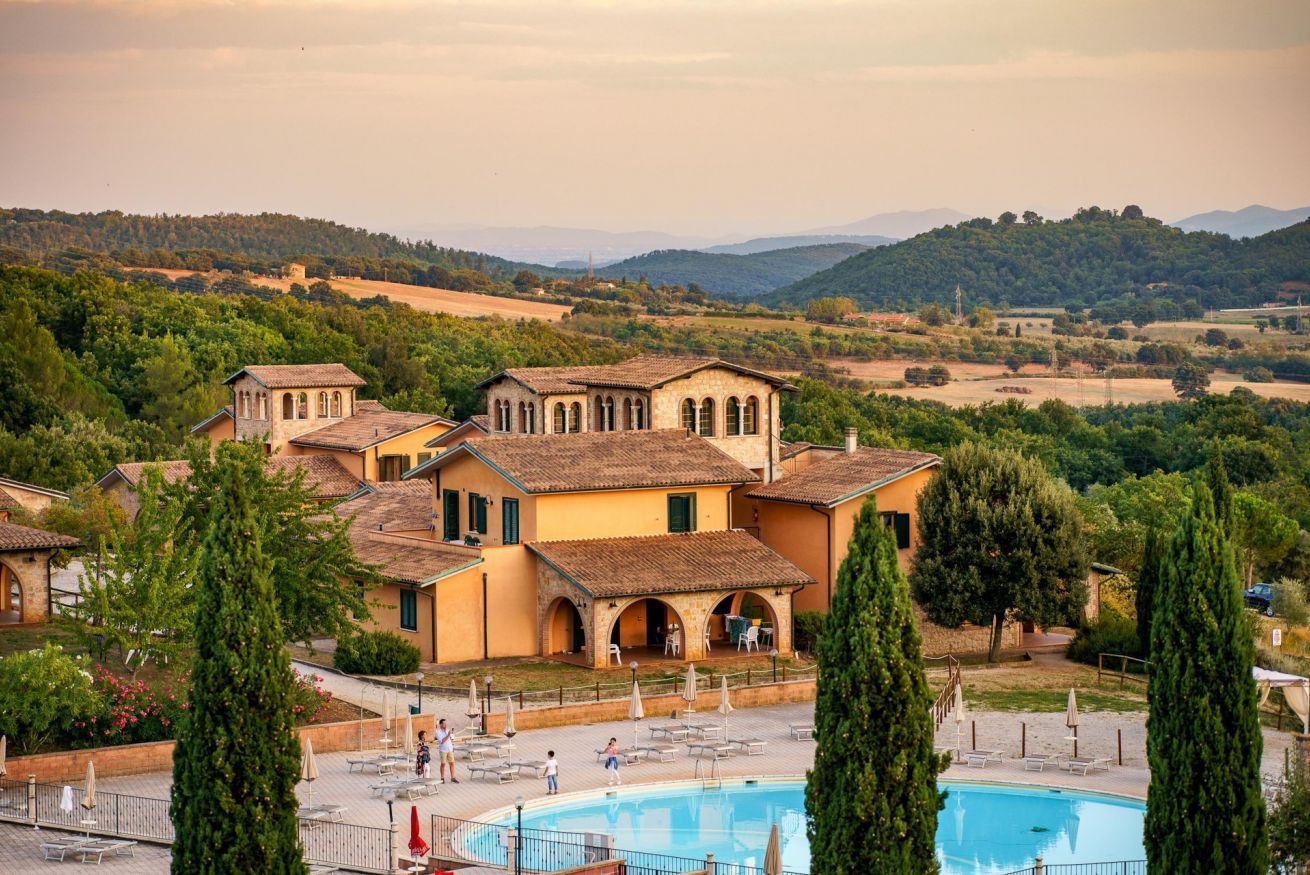 A villa with a swimming pool, surrounded by greenery and hills.