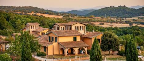 A villa with a swimming pool, surrounded by greenery and hills.