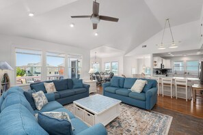 Ein geräumiges Wohnzimmer mit blauen Sofas, einem Couchtisch und einem Deckenventilator.