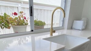 A kitchen with a white countertop, a gold faucet, and a dishwasher.