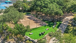 A fenced outdoor area with a grassy lawn, seating arrangements, and a flag. - Escape to Reames Dream BnB: Lakefront bliss with sand volleyball awaits! (Austin)