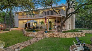 Una casa de dos pisos con balcón, muros de contención de piedra y mobiliario exterior.