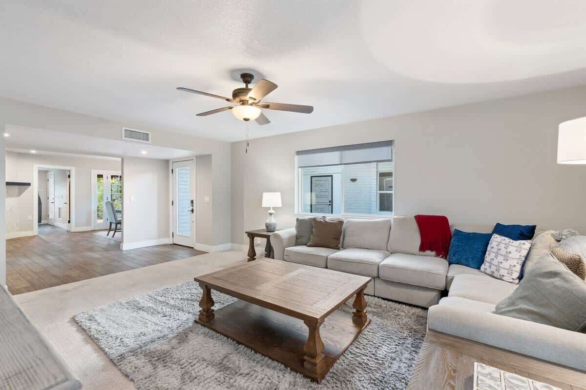 A spacious living room with a ceiling fan, a wooden coffee table, a white sofa, and a red throw blanket.