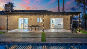 Una casa moderna amb un porxo cobert, mobiliari exterior i una piscina.