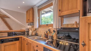 A kitchen with wooden cabinets, a dishwasher, a stove, and a window with curtains.