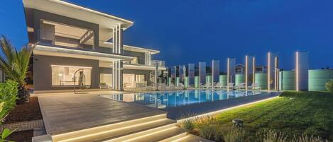 Uma casa moderna de dois andares com piscina, área de estar externa e escadaria bem iluminada.