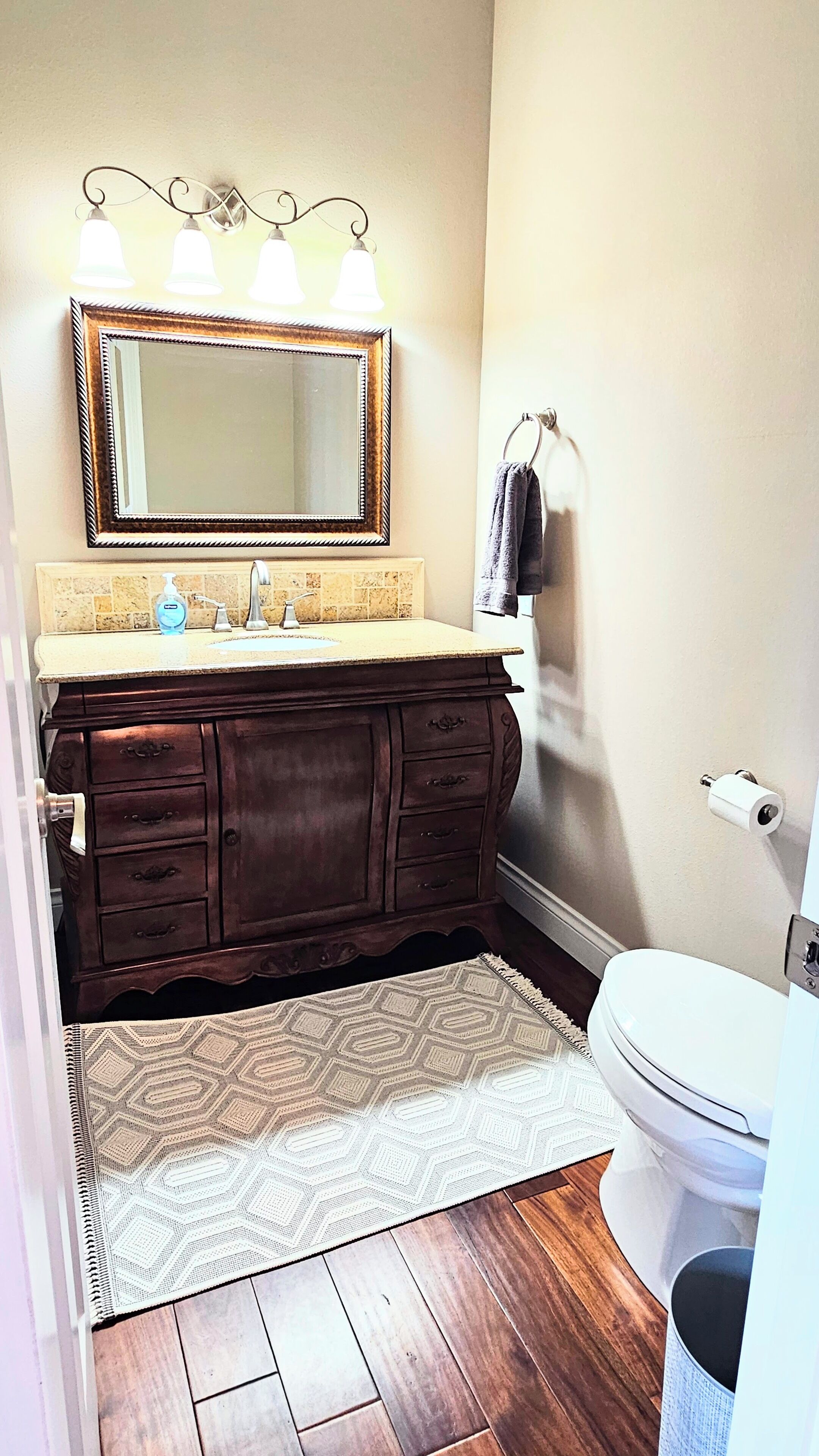 Une salle de bain avec un meuble-lavabo en bois, un grand miroir, un porte-serviettes et des toilettes.