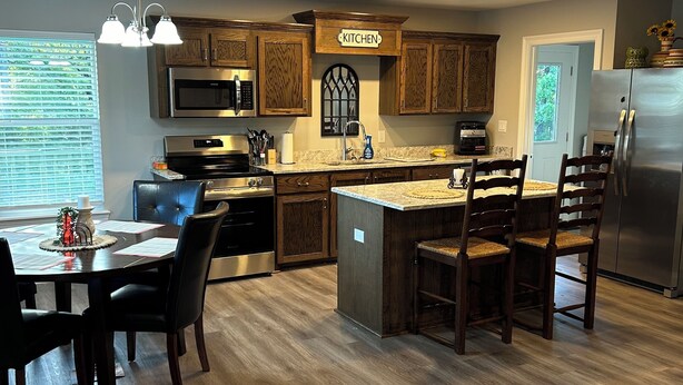 Una cocina moderna con armarios de madera, una isla central y una zona de comedor con mesa y sillas.