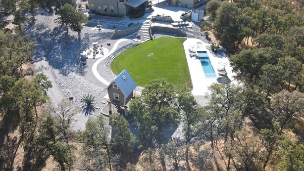 Vista aérea de una extensa propiedad con varias edificaciones, una piscina y un césped bien cuidado.