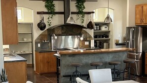 Una cocina moderna con una isla central, taburetes de bar y una zona de comedor con sillas blancas.