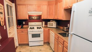 A kitchen with wooden cabinets, a white refrigerator, a stove, a microwave, and a toaster.