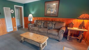 A cozy living room with a brown leather sofa, a wooden coffee table, and a framed picture on the wall.