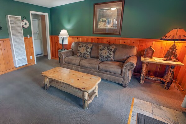 A cozy living room with a brown leather sofa, a wooden coffee table, and a framed picture on the wall. - Townhome with Hot Tub, Easy Walk to Estes #3382 (Estes Park)