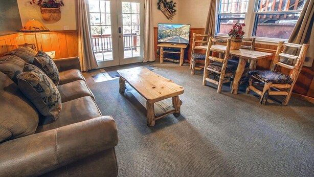 A cozy living room with a leather couch, wooden coffee table, and rustic chairs.