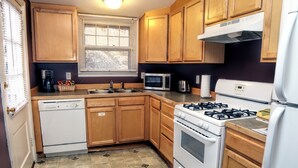 A compact kitchen with wooden cabinets, a microwave, a stove, and a dishwasher. - Walk to Downtown from Spacious Home with Hot Tub #3383 (Estes Park)
