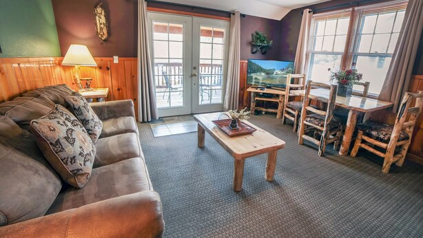 A cozy living room with a sofa, a coffee table, and a dining area with wooden chairs and a table. - Walk to Downtown from Spacious Home with Hot Tub #3383 (Estes Park)