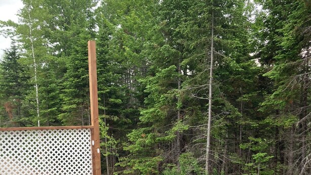 An outdoor hot tub with a wooden deck, surrounded by a wooden fence and red chairs. - Relaxation, Privacy, Hot Tub, Pet Friendly- Kouchibouguac (Kouchibouguac)