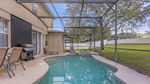 A backyard with a swimming pool, a grill, and a covered patio area.