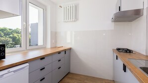 Una cocina moderna con armarios blancos, encimera de madera, horno empotrado y ventana con vistas al exterior.