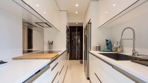 A modern kitchen with white cabinetry, a wooden countertop, and a built-in stove.