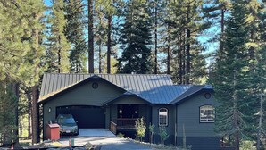 A cabin with a garage, surrounded by tall pine trees. - Relaxing, Spacious 5-bedroom Tahoe Home Monthly Rental (Incline Village)