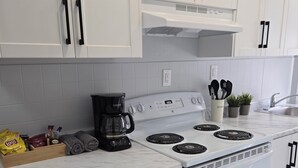 Una cucina con mobili bianchi, un piano cottura bianco e un ripiano in marmo.