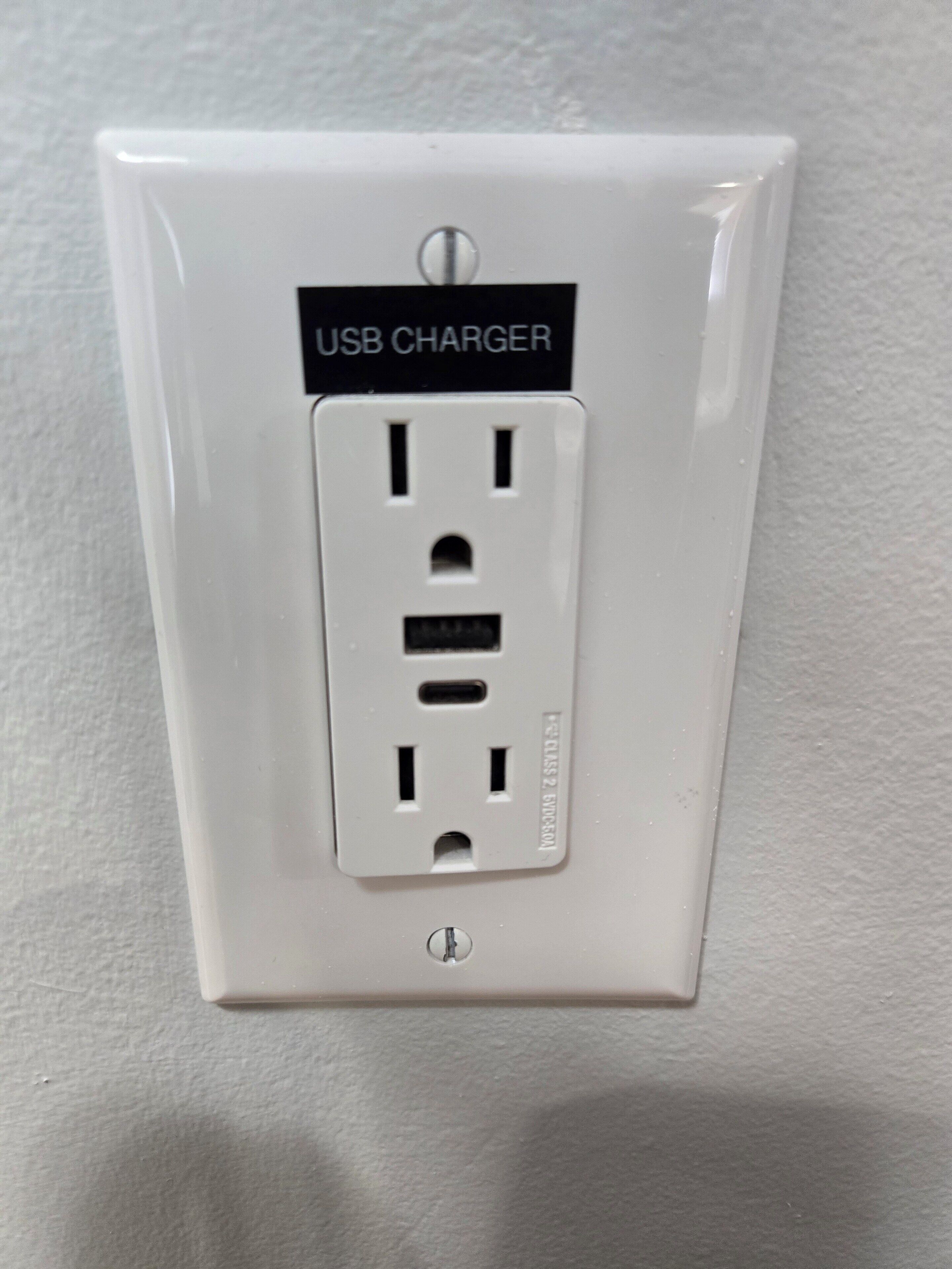 Een witte USB-oplader aan een muur.
