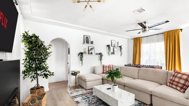 Uma sala de estar moderna com um sofá modular, uma mesa de centro, uma televisão e uma planta.