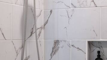 A shower with a handheld showerhead and a wall-mounted control.