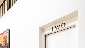 A white door with 'TWO' above it, a bench, and a painting on the wall. - Fabulous Flat in Trussville! (Trussville)