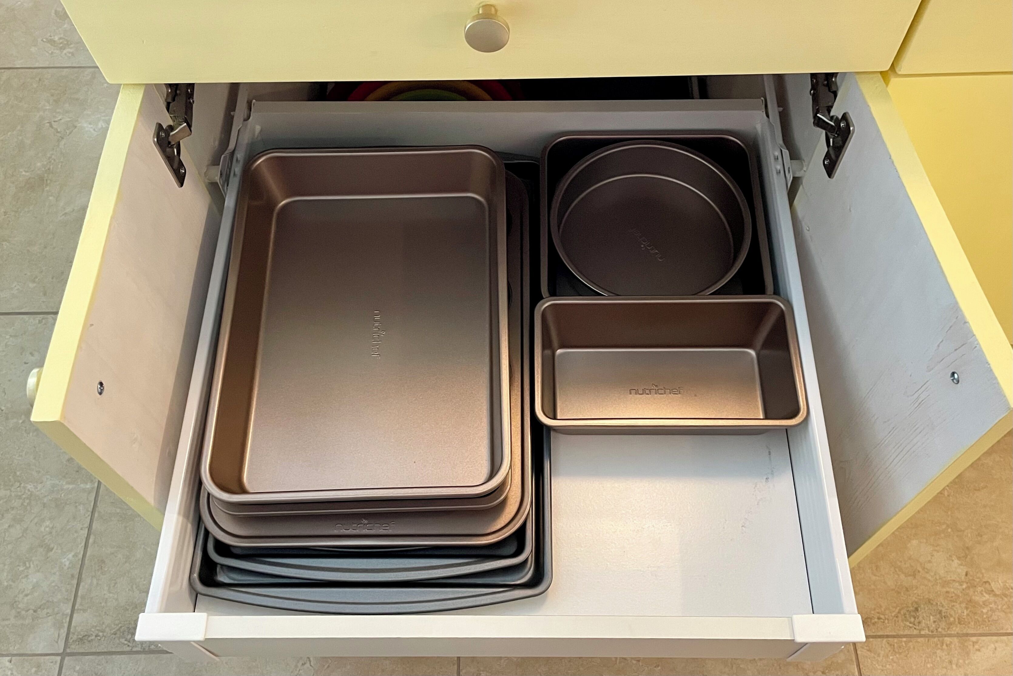 A drawer with various kitchenware items including a large rectangular tray, a smaller rectangular tray, and a round pan.