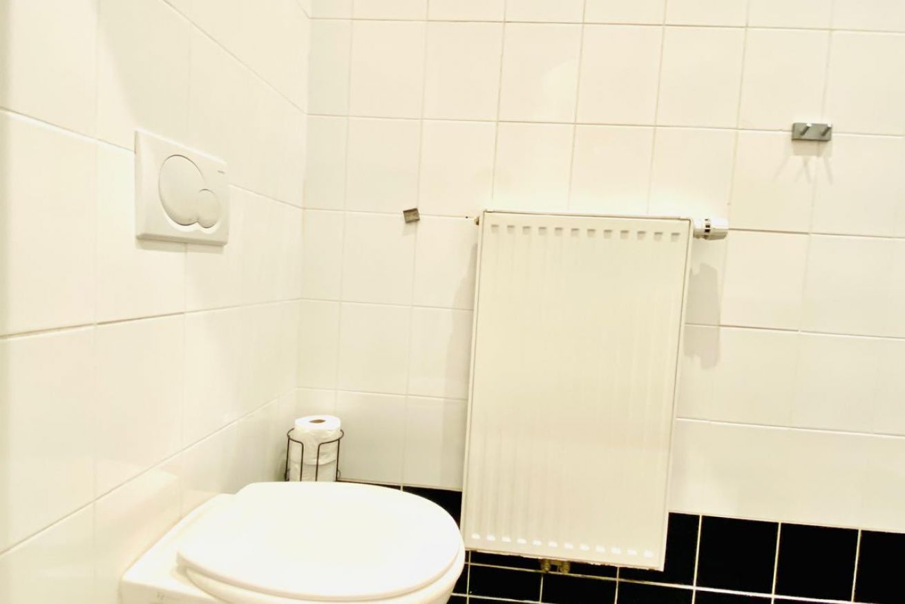 A bathroom with a toilet, a towel rack, and a toilet paper holder.