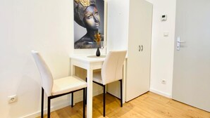 A room with a white desk, two chairs, a painting on the wall, and a closed door. - Ottakring Gem/Cozy Room /w Breathtaking City Views (Vienna)