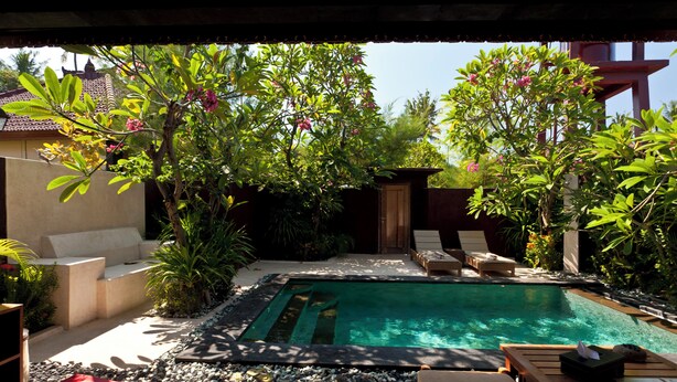 Un espace aménagé au bord de la piscine, comprenant un jacuzzi, des chaises longues et une terrasse en bois.