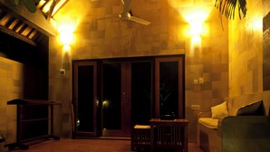 Une terrasse en bois avec un ventilateur de plafond, un canapé et une petite table.