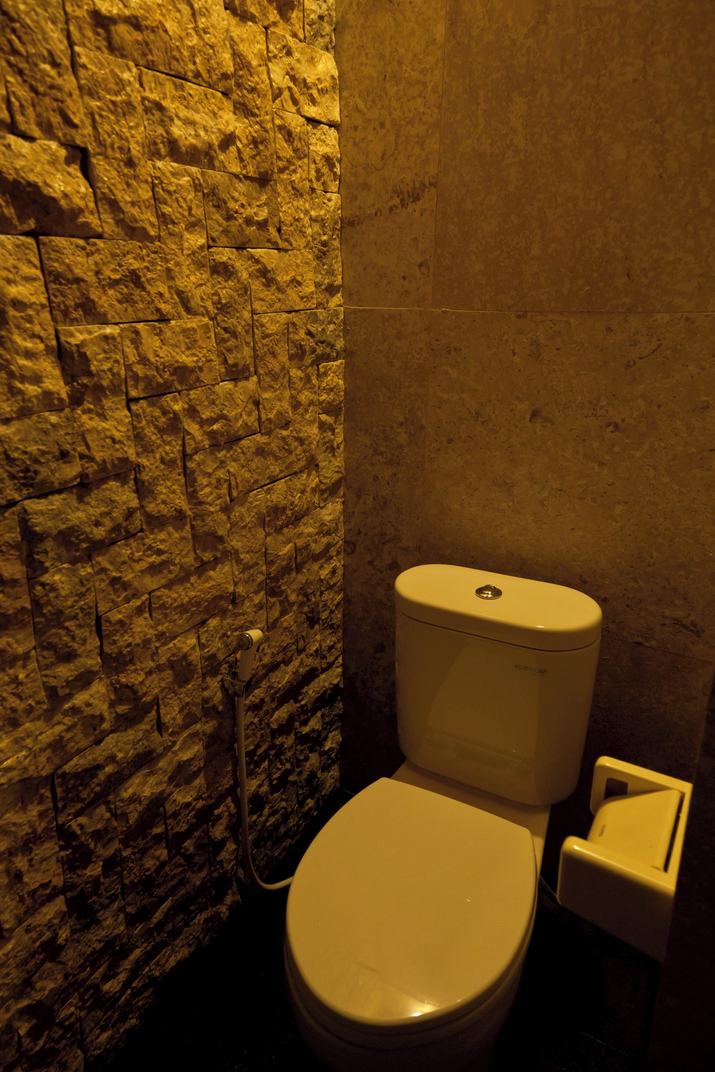 Ein Badezimmer mit einer Steinswand und einer weißen Toilette.