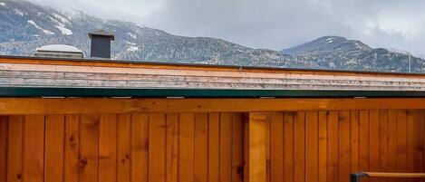 A wooden deck with a view of snow-covered mountains.