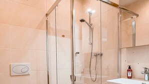 Un baño moderno con ducha de vidrio, inodoro y tocador con espejo.