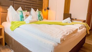 Ein Hotelzimmer mit einem großen Bett, einem Holzkopfstück, einem Kleiderschrank und einem Nachttisch.